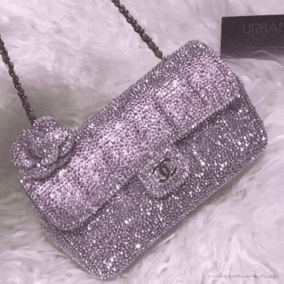 A Purse With A Chanel Logo On It Sits On A White Carpet GIF