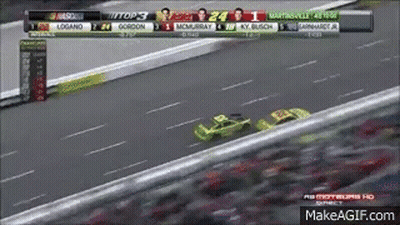 A Race Car Is Driving Down A Race Track With A Scoreboard Behind It . GIF