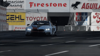A Race Car Is Driving Down A Road In Front Of Signs For Firestone Toyota And Aguila GIF