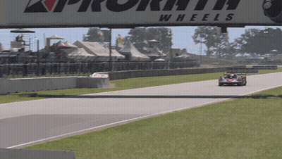 A Race Car Is Driving Down A Track Under A Sign That Says Wheels GIF