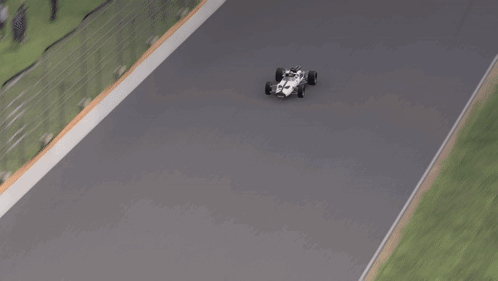A Race Car Is Driving Down A Track With A Grassy Area In The Background GIF