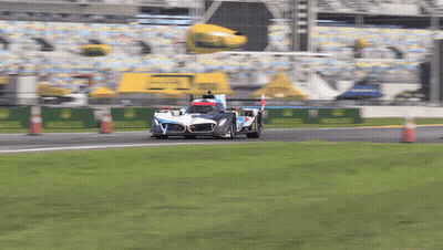 A Race Car Is Driving Down A Track With A Yellow Banner That Says Rolex On It GIF