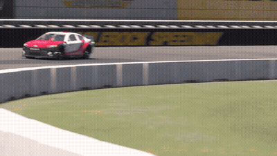 A Race Car Is Going Around A Curve On A Track With A Sign That Says Rock Speedway In The Background GIF