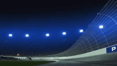 A Race Track Is Lit Up At Night With A Lot Of Lights On It . GIF