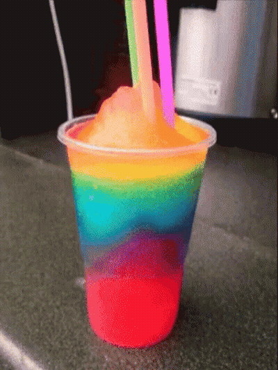 A Rainbow Colored Drink In A Plastic Cup With Two Straws GIF
