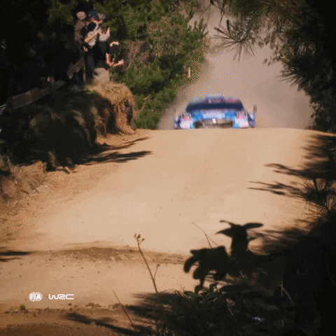 A Rally Car Is Driving Down A Dirt Road With A W2c Logo In The Corner GIF