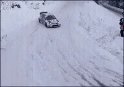 A Rally Car Is Driving Through The Snow On A Track . GIF