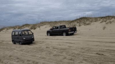 A Ram Truck And A Van Are Parked On A Sandy Beach GIF