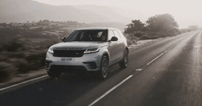 A Range Rover Is Driving Down The Road GIF