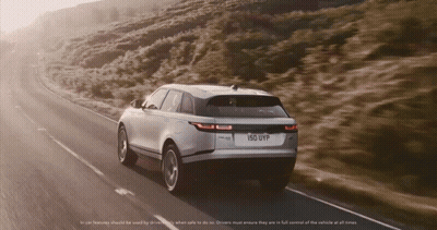 A Range Rover Velar Is Driving Down A Road GIF