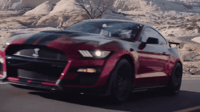 A Red And Black Mustang Is Driving Down A Desert Road GIF