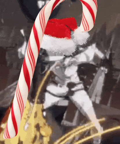 A Red And White Candy Cane With A Santa Hat On GIF