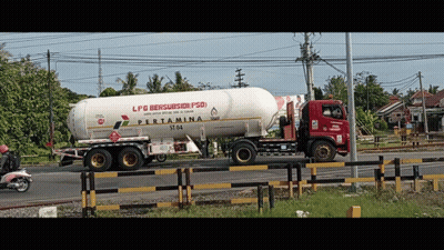 A Red And White Pertamina Truck Is Driving Down A Road GIF