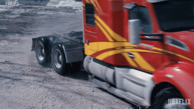 A Red And Yellow Semi Truck Is Driving Down A Dirt Road With Netflix Written On The Bottom GIF