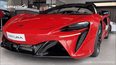 A Red Artura Sports Car Is Displayed In A Namaste Car Showroom GIF