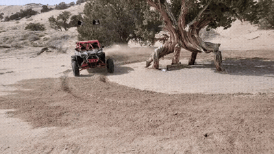 A Red Atv Is Driving Down A Dirt Road GIF
