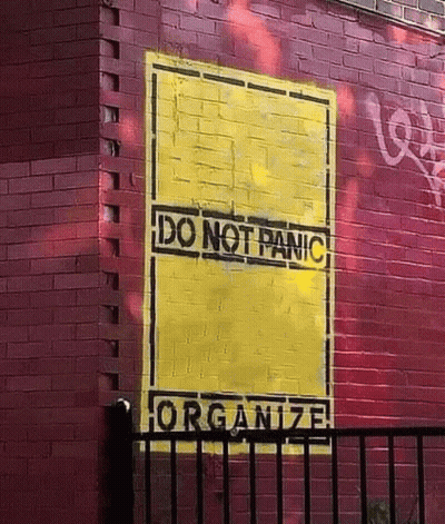 A Red Brick Wall With A Yellow Sign That Says Do Not Panic GIF