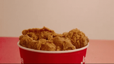 A Red Bucket Filled With Fried Chicken Has The Word Jc On It GIF