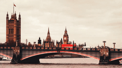 A Red Bus Is Crossing A Bridge In Front Of Big Ben In London GIF