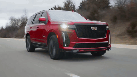 A Red Cadillac Is Driving Down A Highway GIF