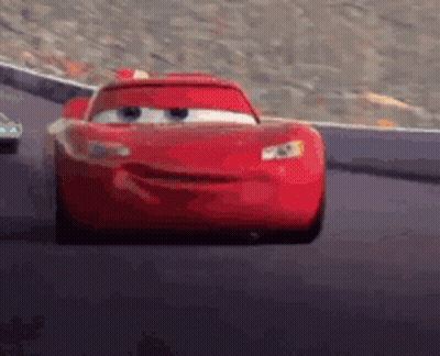 A Red Car From The Movie Cars Is Driving Down A Track . GIF