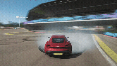 A Red Car Is Drifting On A Race Track With A Festival Site Displayed In The Background GIF