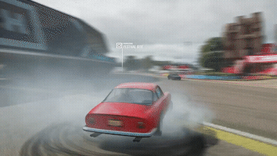 A Red Car Is Drifting On A Race Track With A Festival Site Displayed In The Background GIF