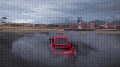 A Red Car Is Drifting On A Track And Smoke Is Coming Out Of It GIF