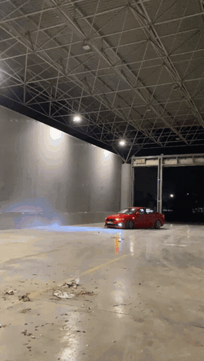A Red Car Is Driving Down A Concrete Road GIF