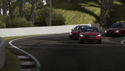 A Red Car Is Driving Down A Road With A White Wall Behind It GIF