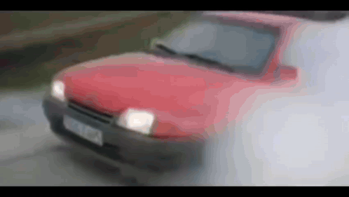 A Red Car Is Driving Down A Road With Smoke Coming Out Of The Hood And Windshield GIF