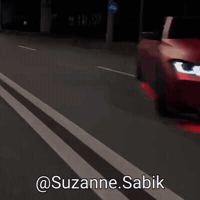A Red Car Is Driving Down A Street With The Words @Suzanne.sabik Written On The Bottom GIF