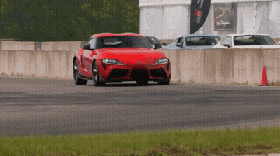 A Red Car Is Driving On A Track With A Sign That Says Greddy GIF