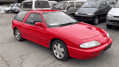 A Red Car Is Parked In A Parking Lot Surrounded By Other Cars GIF