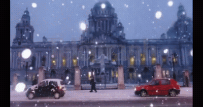A Red Car Is Parked In Front Of A Building In The Snow GIF