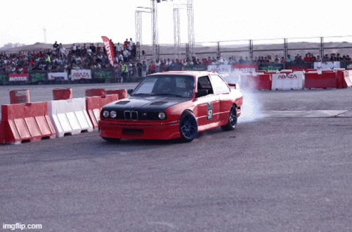 A Red Car With The Number 57 On The Side Is Driving Down A Track GIF