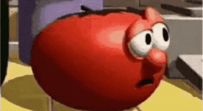 A Red Cartoon Tomato With Big Eyes And A Red Nose Is Sitting On A Yellow Table . GIF