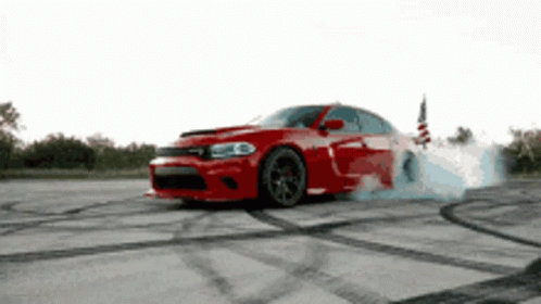 A Red Dodge Charger Is Drifting On A Concrete Surface GIF