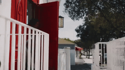 A Red Door With A White Railing Is Open To A White House GIF