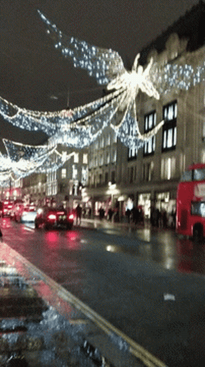 A Red Double Decker Bus Is Driving Down A Busy Street GIF