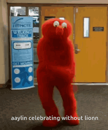 A Red Elmo Mascot Is Dancing In Front Of A Walking Track Sign GIF