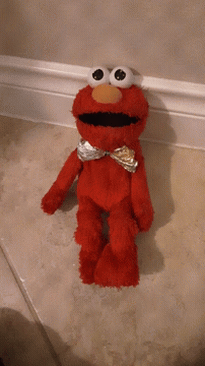 A Red Elmo Stuffed Animal Is Standing On A Tiled Floor GIF