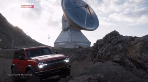A Red Ford Bronco Is Parked In Front Of A Large Antenna In A Video Game Called Horizon 5 GIF