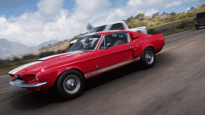 A Red Ford Mustang Gt500 Is Driving Down The Road GIF