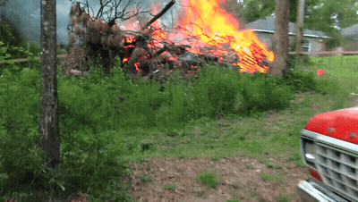 A Red Ford Truck Is Parked In Front Of A Large Pile Of Fire GIF