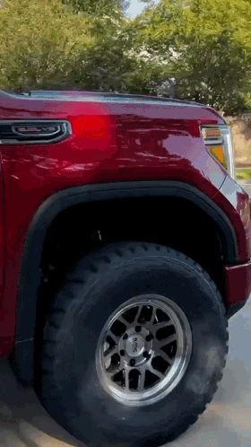 A Red Gmc Truck Is Parked On The Side Of A Road GIF