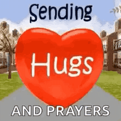 A Red Heart With The Words `` Sending Hugs And Prayers '' Written On It Is Sitting On A Sidewalk . GIF