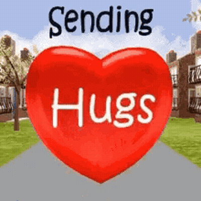 A Red Heart With The Words `` Sending Hugs '' Written On It Is Sitting On A Sidewalk . GIF