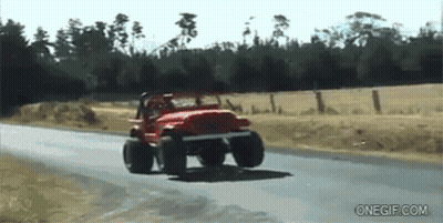 A Red Jeep Is Driving Down A Road Next To A Field GIF