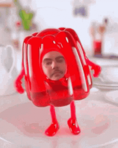 A Red Jelly With A Man 'S Face On It Is Standing On A White Plate . GIF